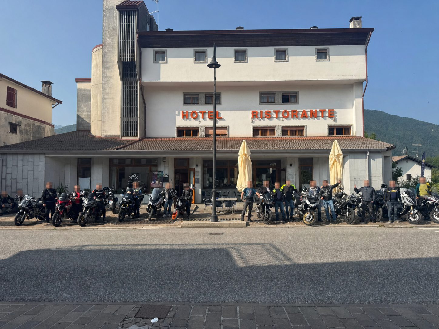 Gruppo di motociclisti davanti al Bike & Bikers Hotel con volti pixelati